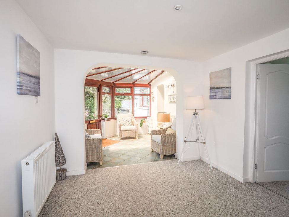 A conservatory with seating and a view of the garden at Bryn Llifon in Pentraeth