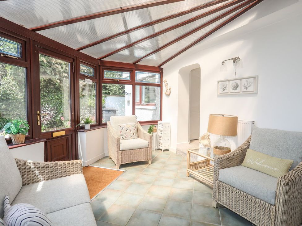 A conservatory with seating and plants at Bryn Llifon in Pentraeth