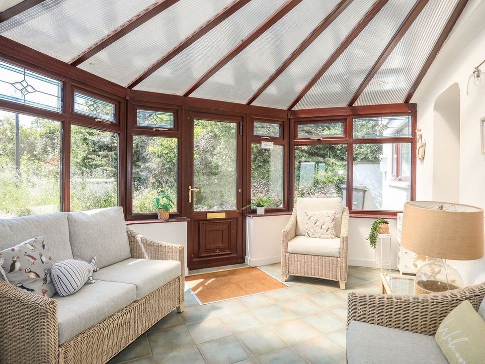 A conservatory with seating and plants at Bryn Llifon in Pentraeth