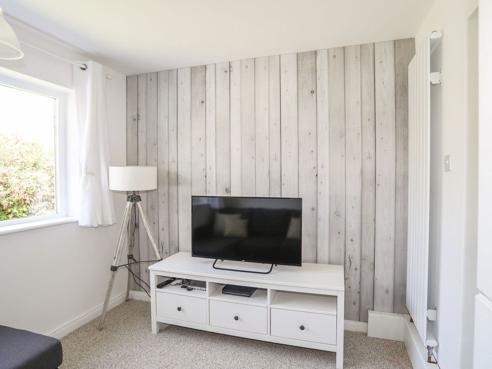 A living room with a television and lamp at Bryn Llifon in Pentraeth