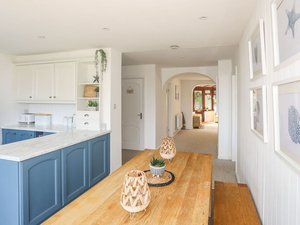 A kitchen with a table and chairs at Bryn Llifon in Pentraeth