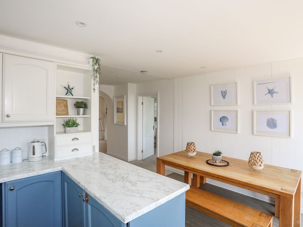 A kitchen with a wooden dining table and decorative items at Bryn Llifon in Pentraeth