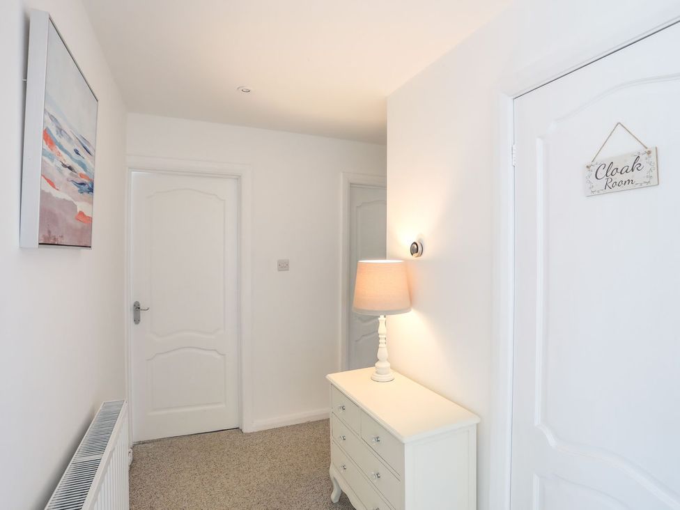 A hallway with a lamp and chest of drawers at Bryn Llifon in Pentraeth