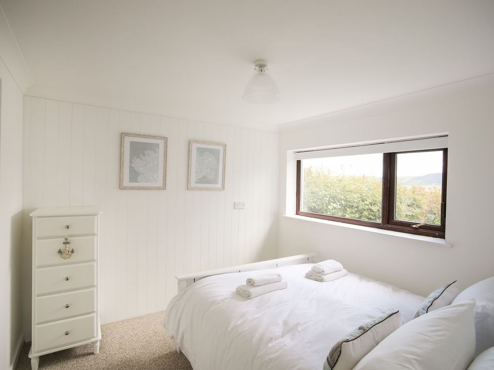 A bedroom with a bed and dresser at Bryn Llifon in Pentraeth