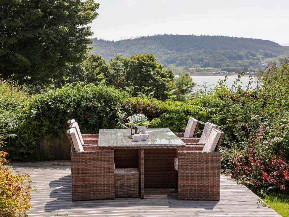 An outdoor dining area with wicker furniture and a view at Bryn Llifon in Pentraeth