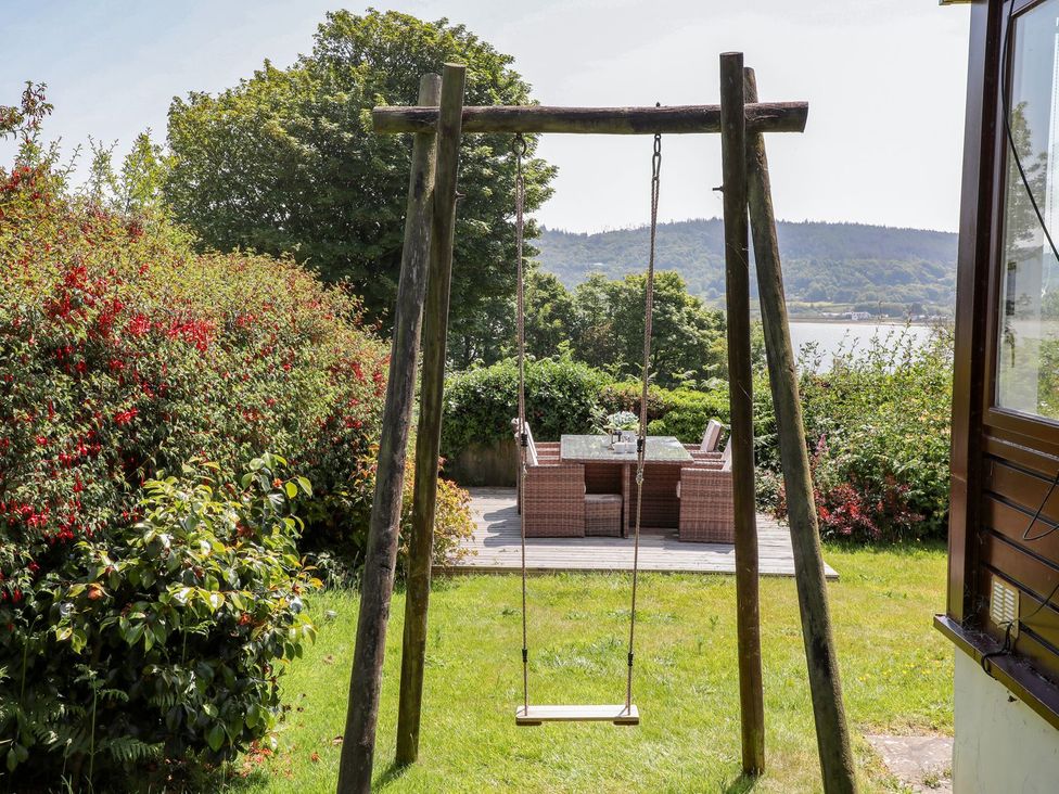 A garden with a swing and outdoor furniture at Bryn Llifon in Pentraeth