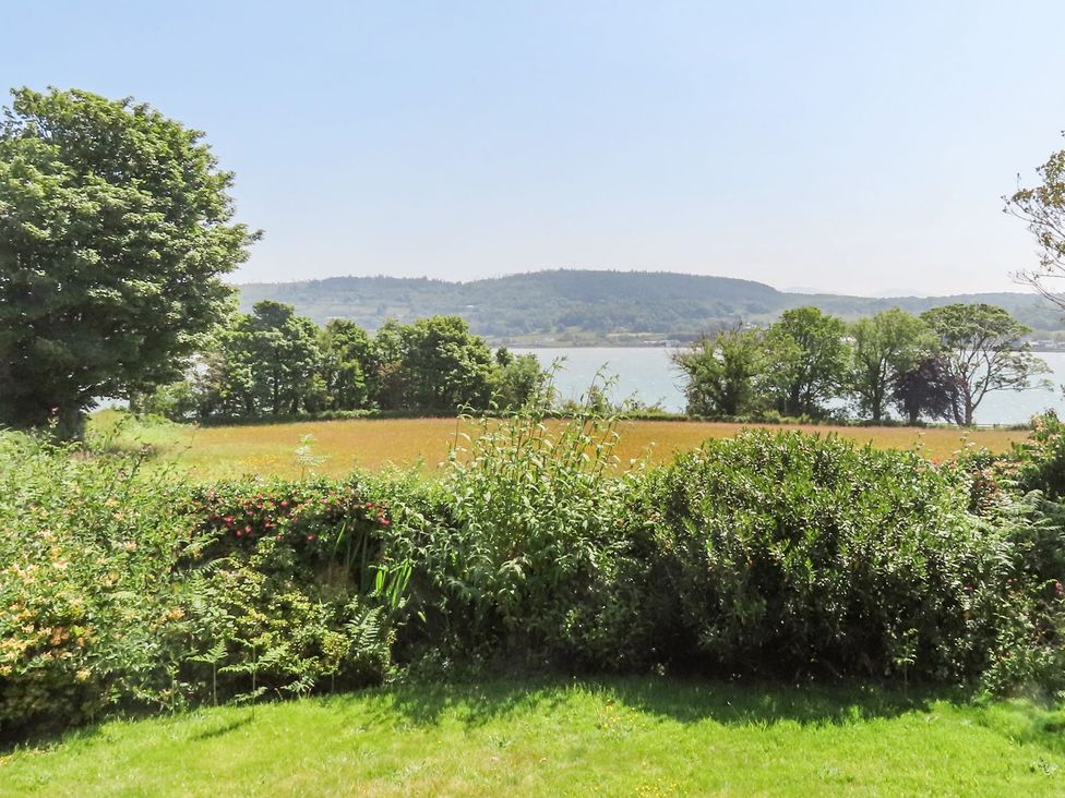 A garden view with trees and water at Bryn Llifon in Pentraeth