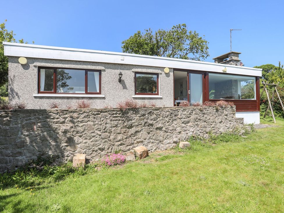 A house with windows and a stone wall at Bryn Llifon in Pentraeth