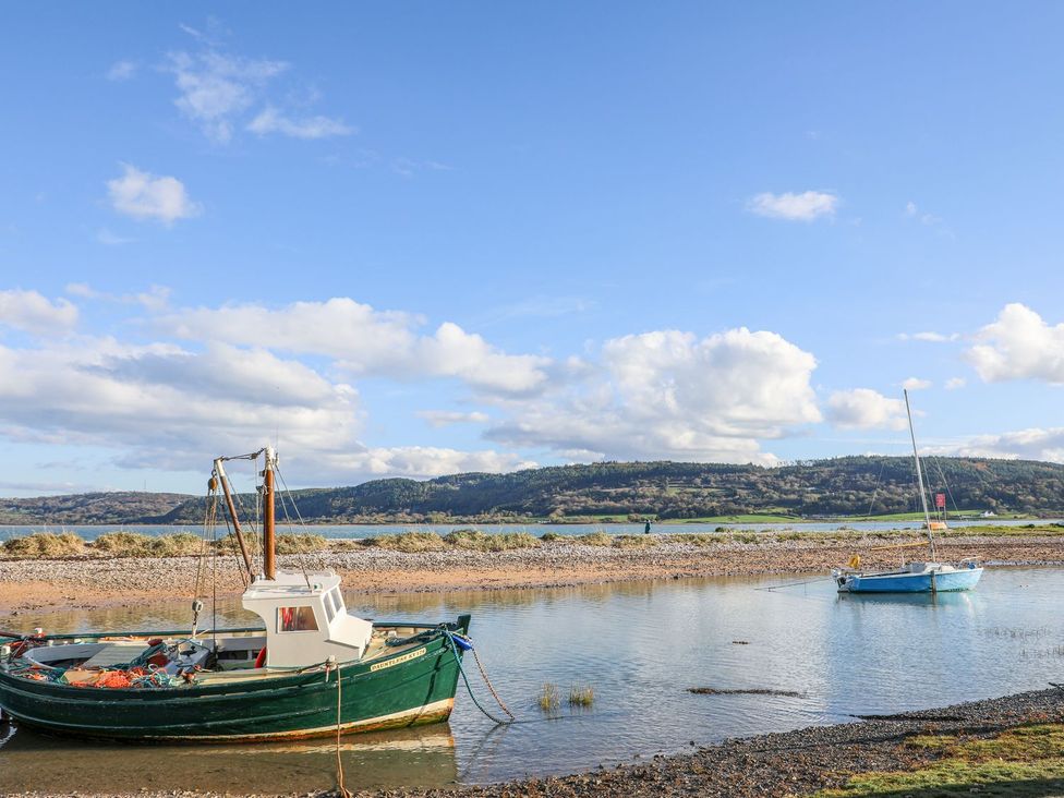 A fishing boat and a sailboat on the water at Bryn Llifon in Pentraeth