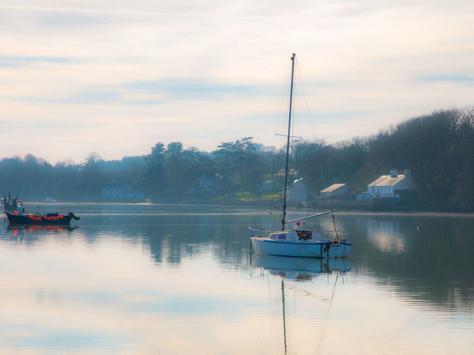 A sailboat and a fishing boat on water at Bryn Llifon in Pentraeth