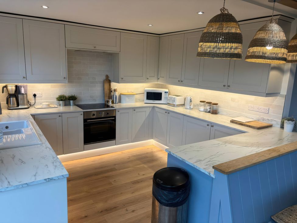 A kitchen with cabinets, sink, and appliances at Red Wharf Retreat in Red Wharf Bay near Benllech