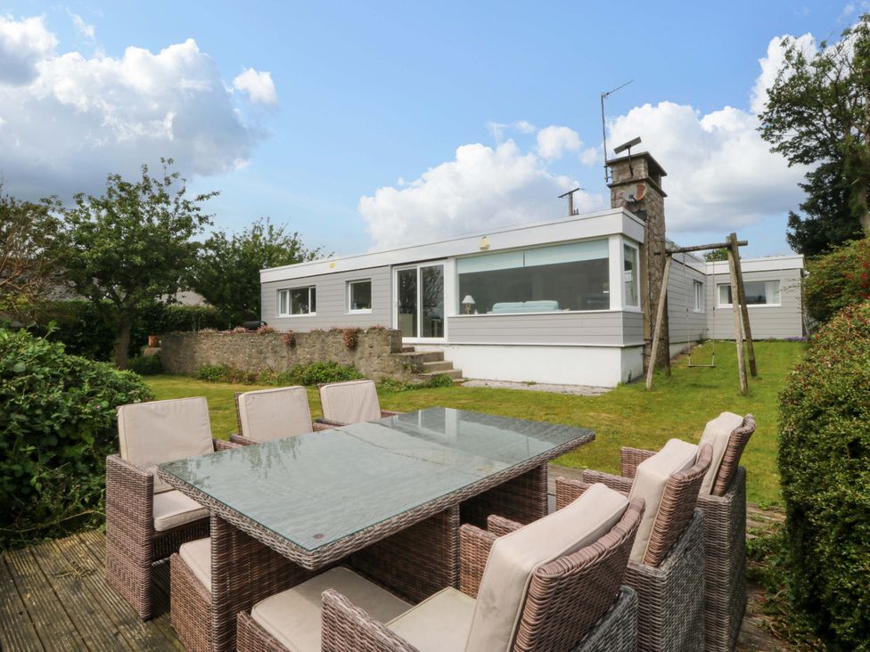 A garden with a dining table and chairs at Red Wharf Retreat in Red Wharf Bay near Benllech