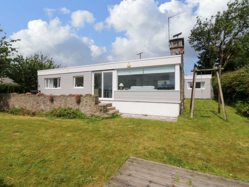A house with a garden and swing at Red Wharf Retreat near Red Wharf Bay