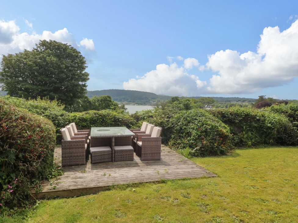 A garden with a table and chairs overlooking a view at Red Wharf Retreat near Red Wharf Bay