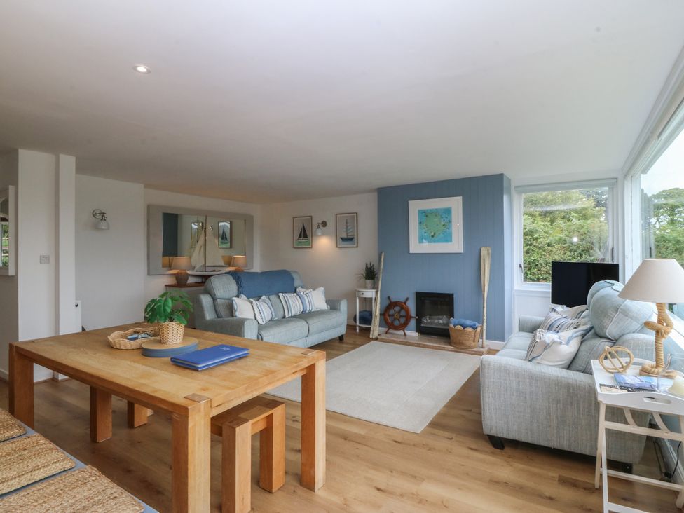 A living room with a sofa, dining table and TV at Red Wharf Retreat in Red Wharf Bay near Benllech