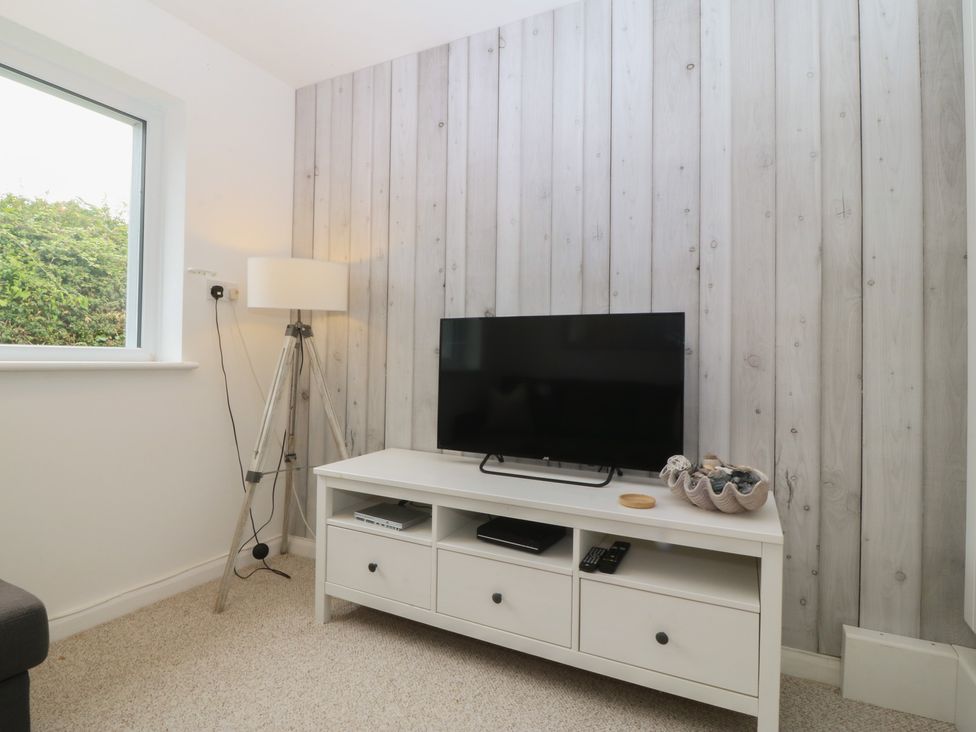 A living room with a TV and lamp at Red Wharf Retreat in Red Wharf Bay near Benllech