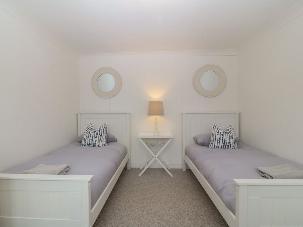 A bedroom with two single beds and a table with a lamp at Red Wharf Retreat in Red Wharf Bay near Benllech