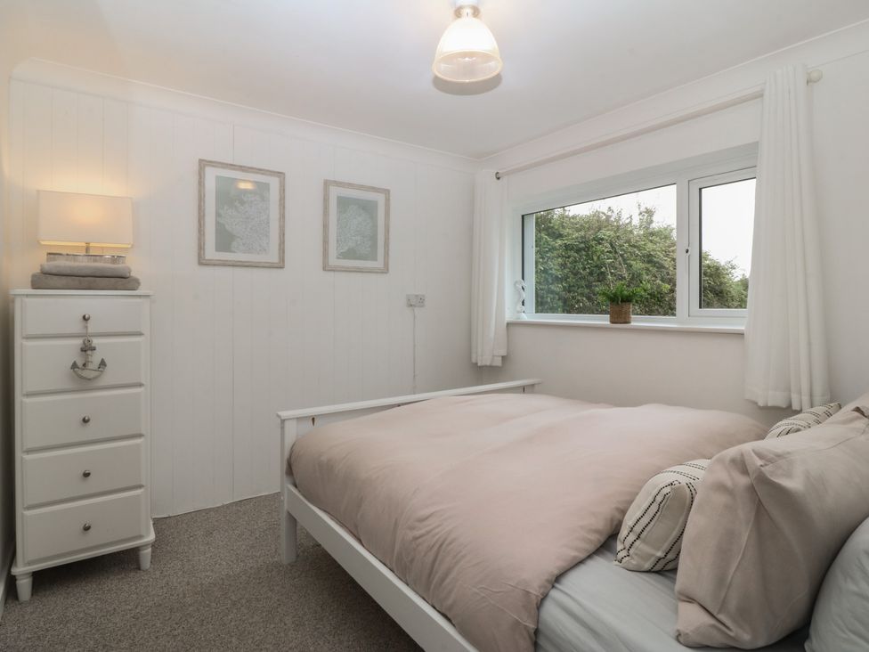 A bedroom with a bed and bedside lamp at Red Wharf Retreat near Benllech