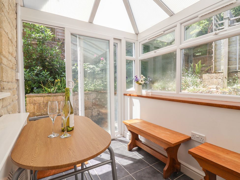 A conservatory with a table and benches at Seaview in Lyme Regis
