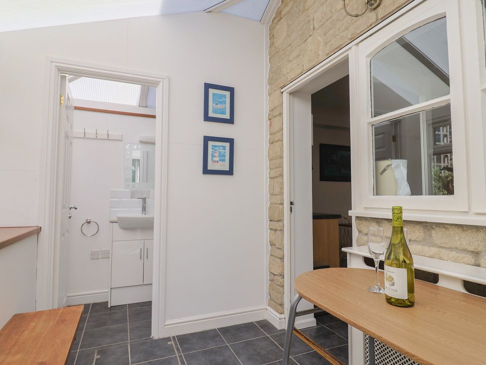 A conservatory with a table and wine glasses at Seaview in Lyme Regis