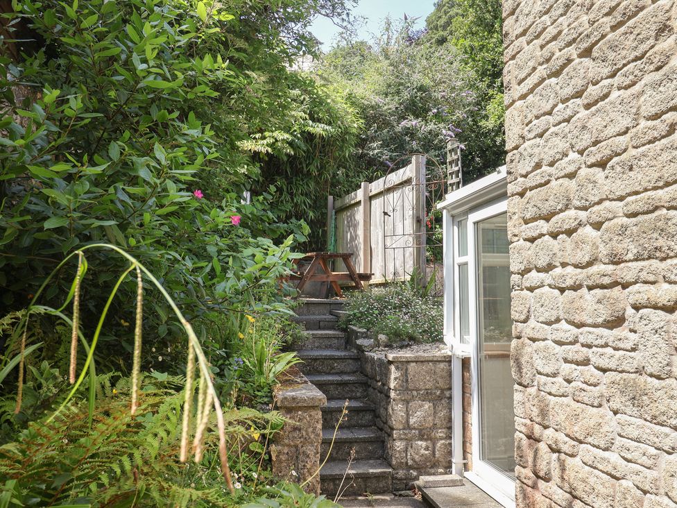 A garden with stairs leading to a table and plants at Seaview in Lyme Regis