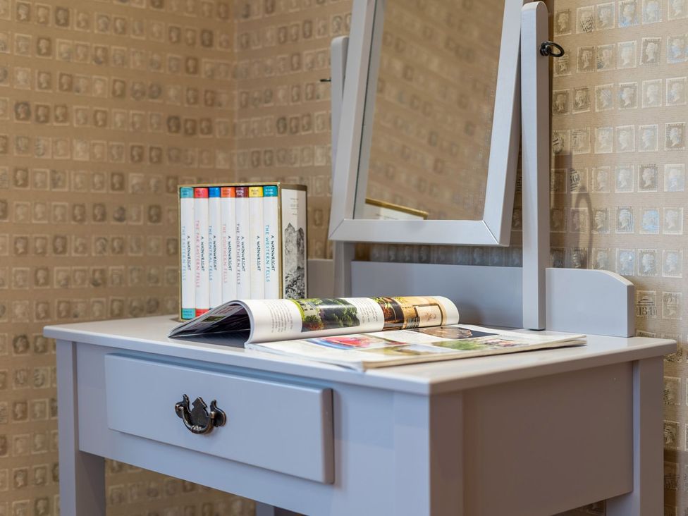 A vanity table with a mirror and books at Prospect House in Windermere