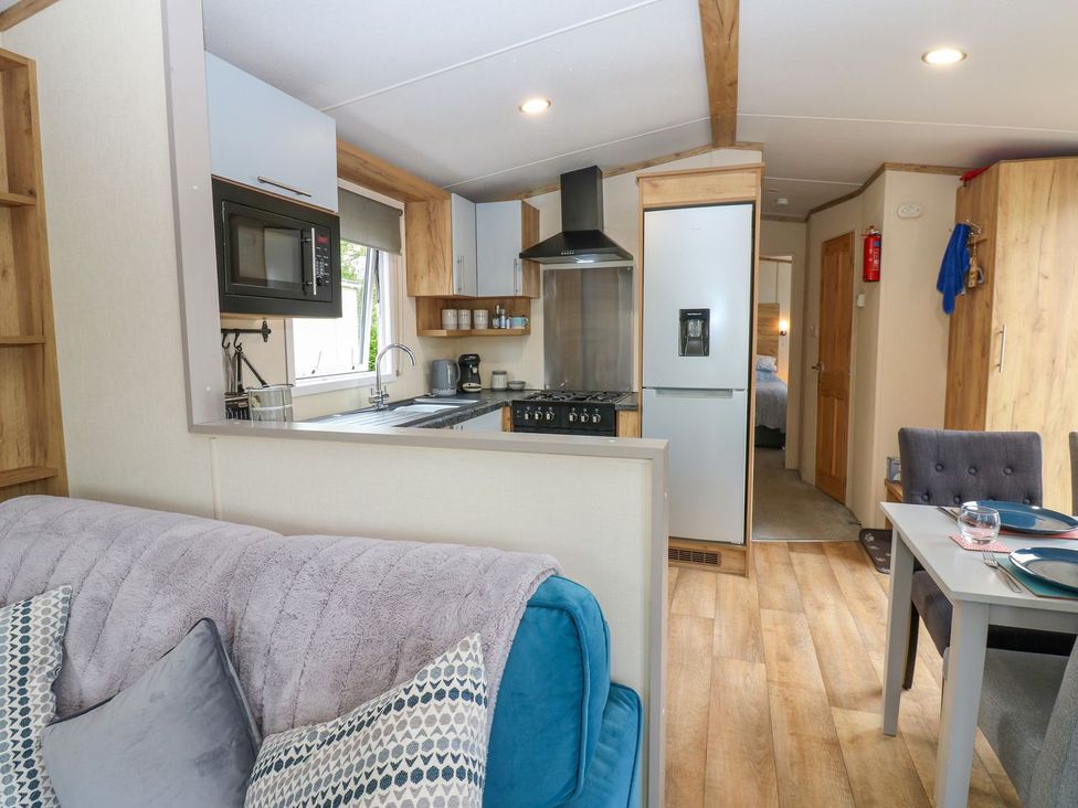 A kitchen with a stove, fridge, and dining area at Plot 41 High Hesket near Armathwaite