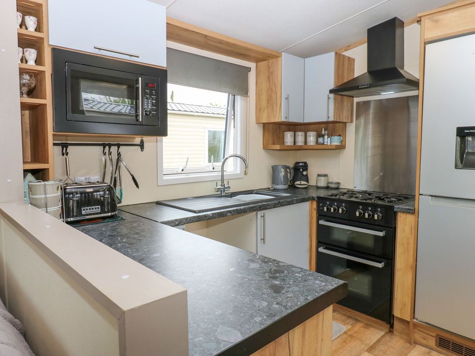 A kitchen with a microwave, stove, and sink at Plot 41 High Hesket near Armathwaite