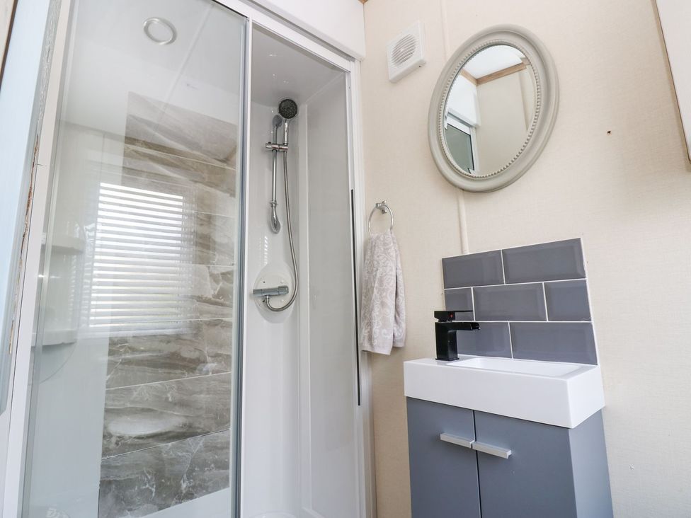 A bathroom featuring a shower, sink with cabinet, and a mirror at Plot 41 High Hesket near Armathwaite