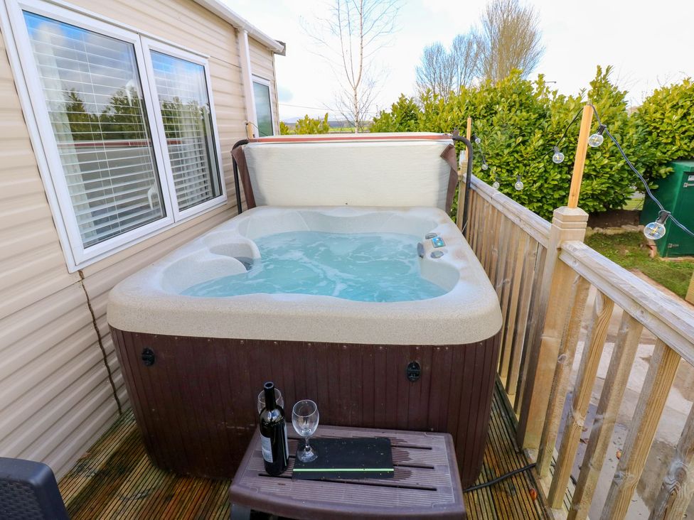 An outdoor hot tub with wine on a table at Plot 41 High Hesket near Armathwaite
