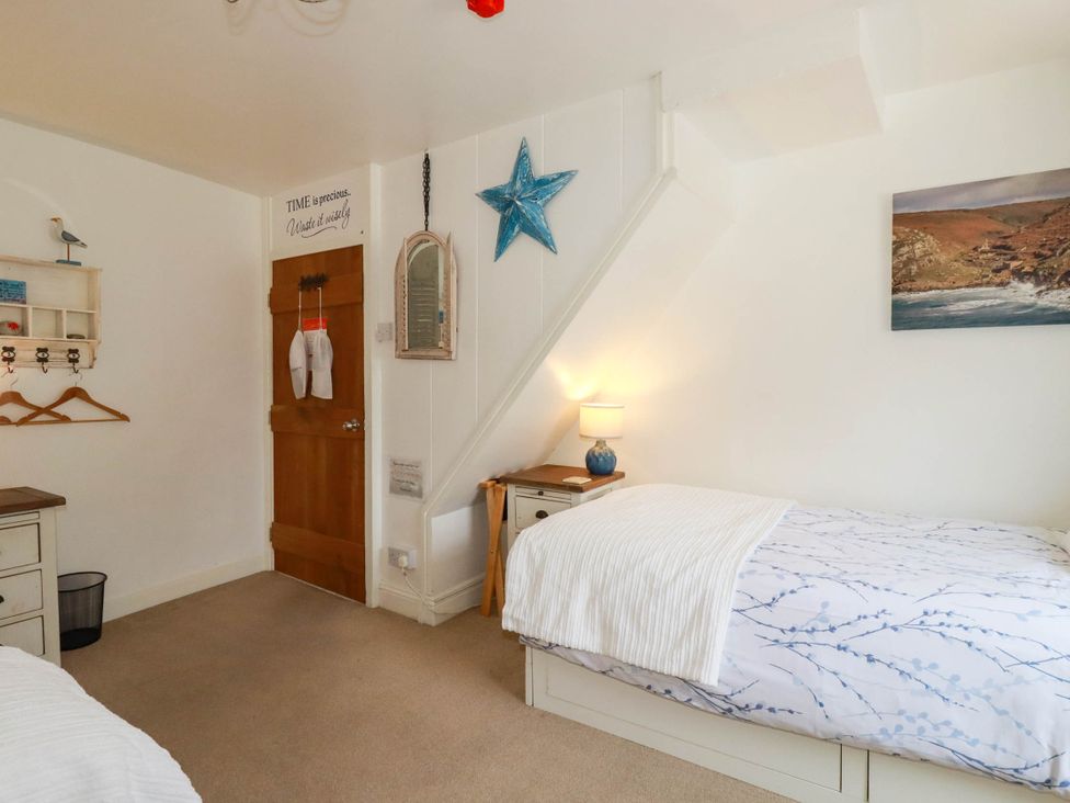 A bedroom with a bed and lamp at Stones Throw in Mevagissey