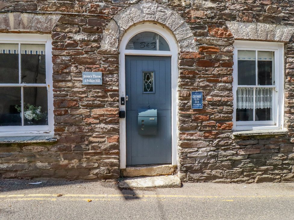 A stone wall with a blue door and windows at Stones Throw in Mevagissey