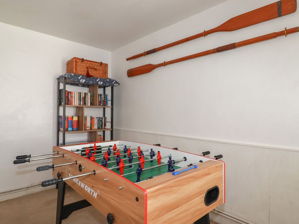 A game room with a foosball table and bookshelf at Stones Throw in Mevagissey
