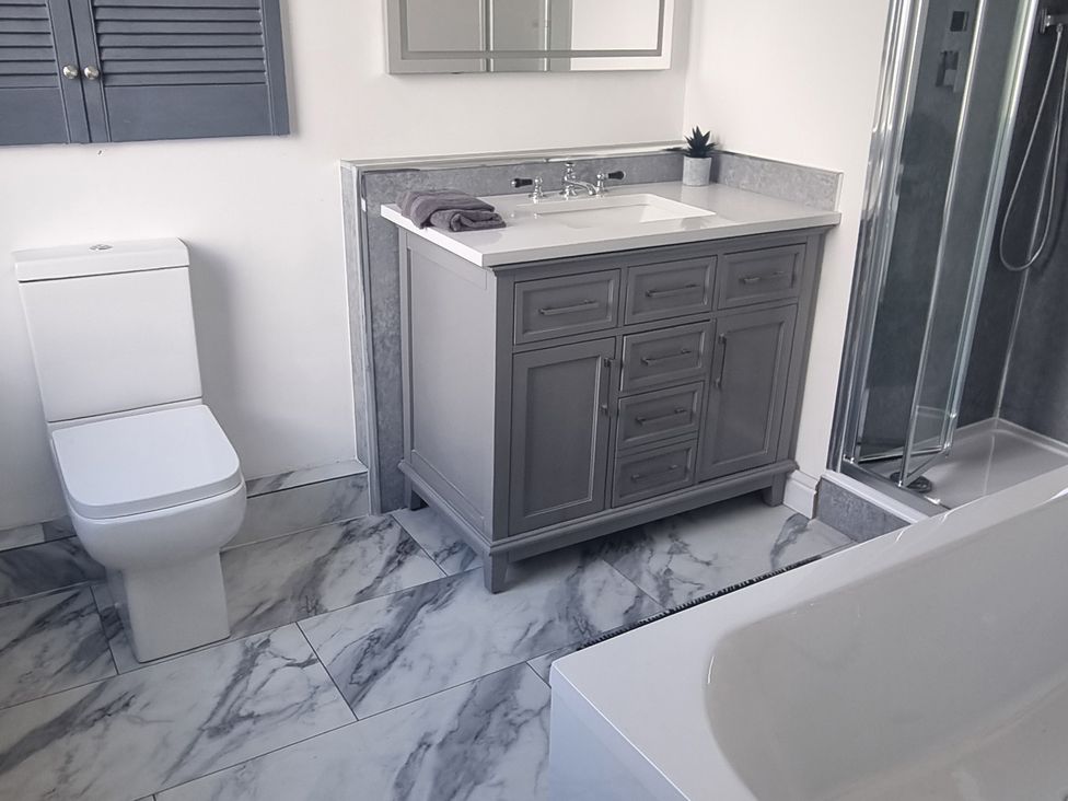 A bathroom with a sink, toilet, shower, and bathtub at 3 Greystone Terrace in Cleator Moor
