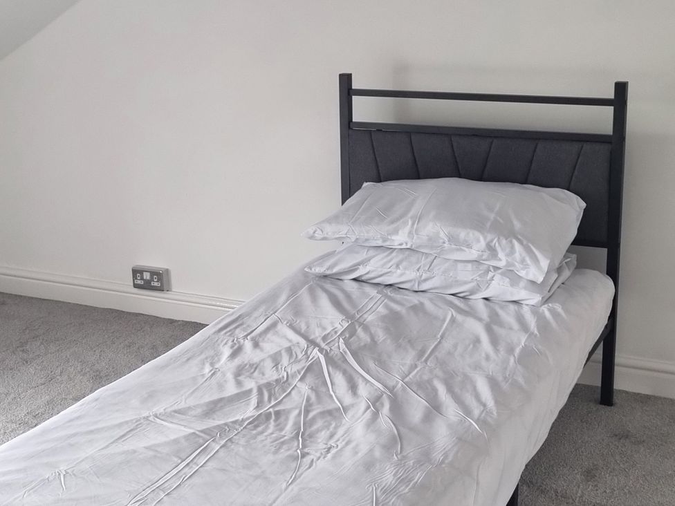 A bed with pillows and sheets in a bedroom at 3 Greystone Terrace in Cleator Moor