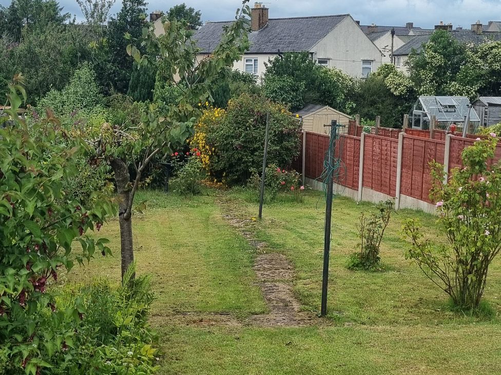 A garden with a path, trees, and a greenhouse at 3 Greystone Terrace in Cleator Moor