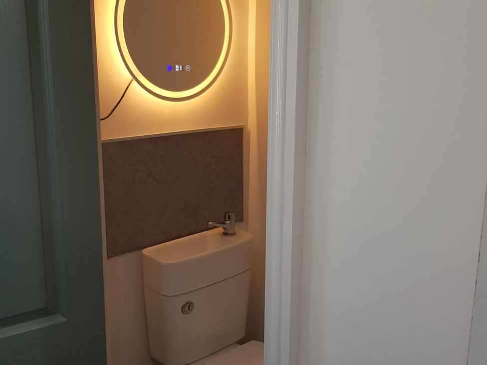 A bathroom with a toilet and a mirror at Ehen Cottage in Cleator Moor