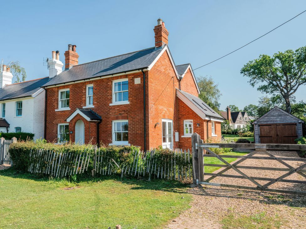 An exterior view of a red brick house with a fence and garden at TBC