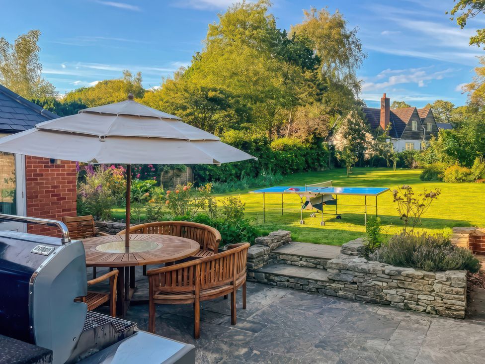 A garden with a table and chairs under a parasol at TBC 