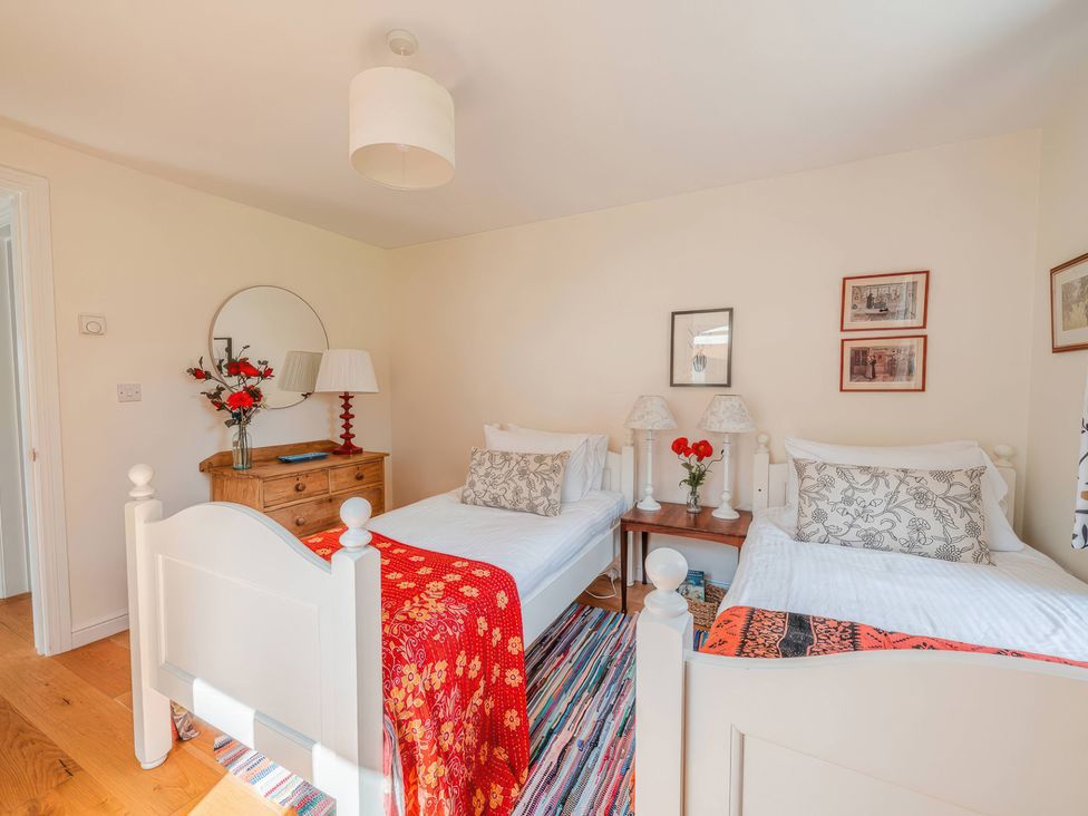 A bedroom with two beds and a chest of drawers at TBC