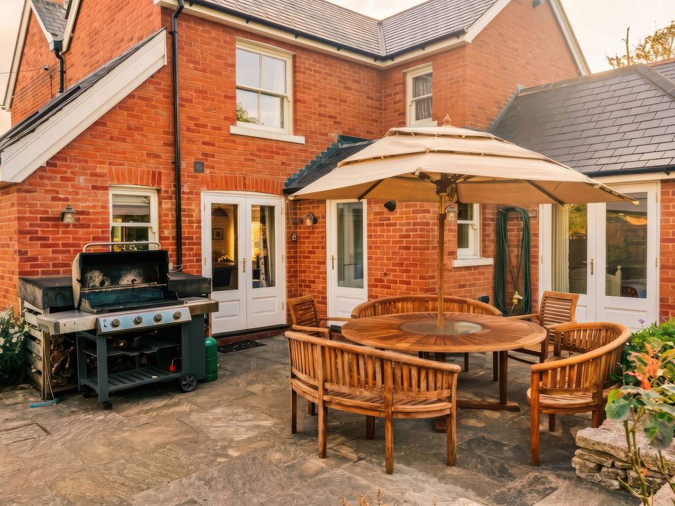 A garden with a wooden table and chairs under an umbrella at TBC 