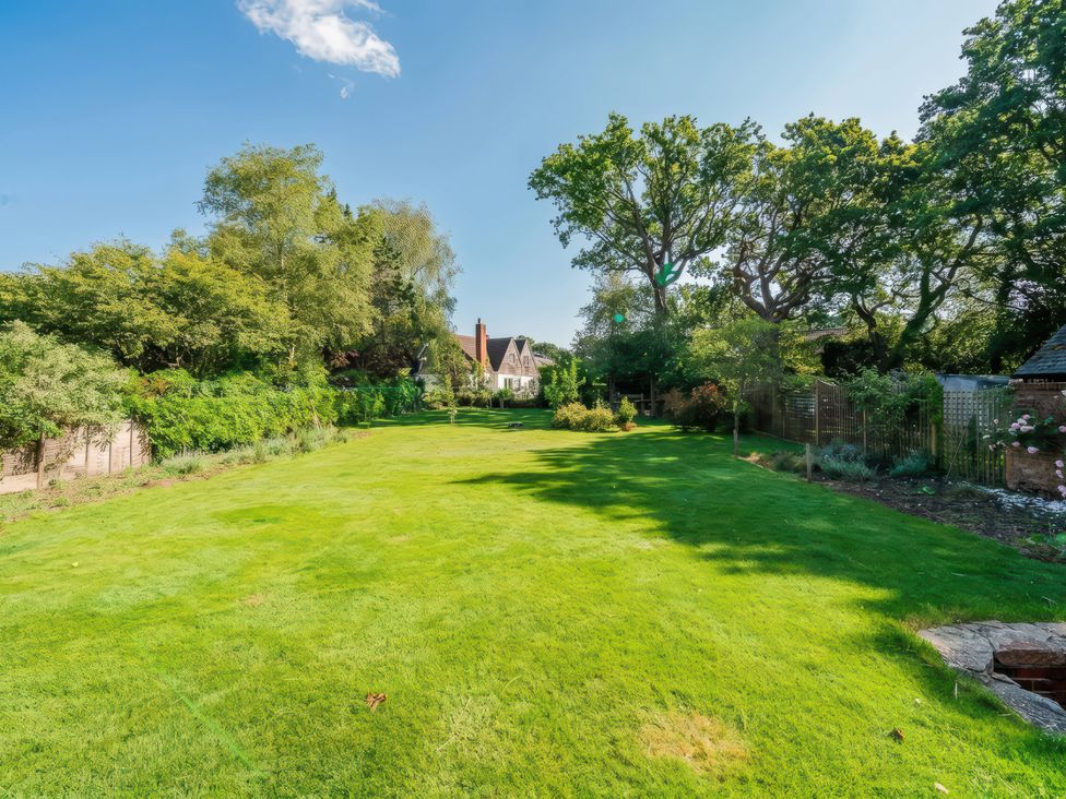 A garden with a large lawn and trees at TBC in 