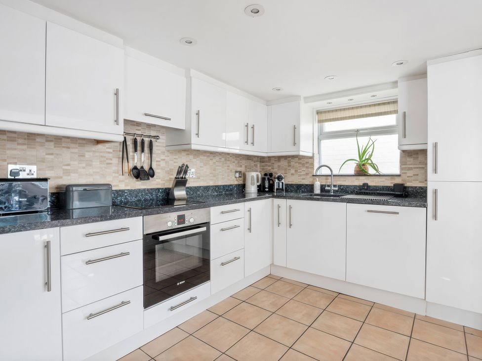 A kitchen with cabinets, countertop, sink, kettle, and coffee maker at TBC