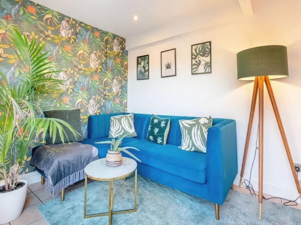 A living room with a blue sofa and plant at TBC