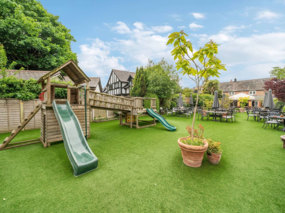 A garden with a playground and seating area at TBC