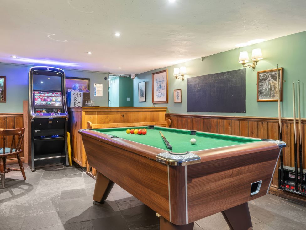 A game room with a pool table and gaming machine at TBC
