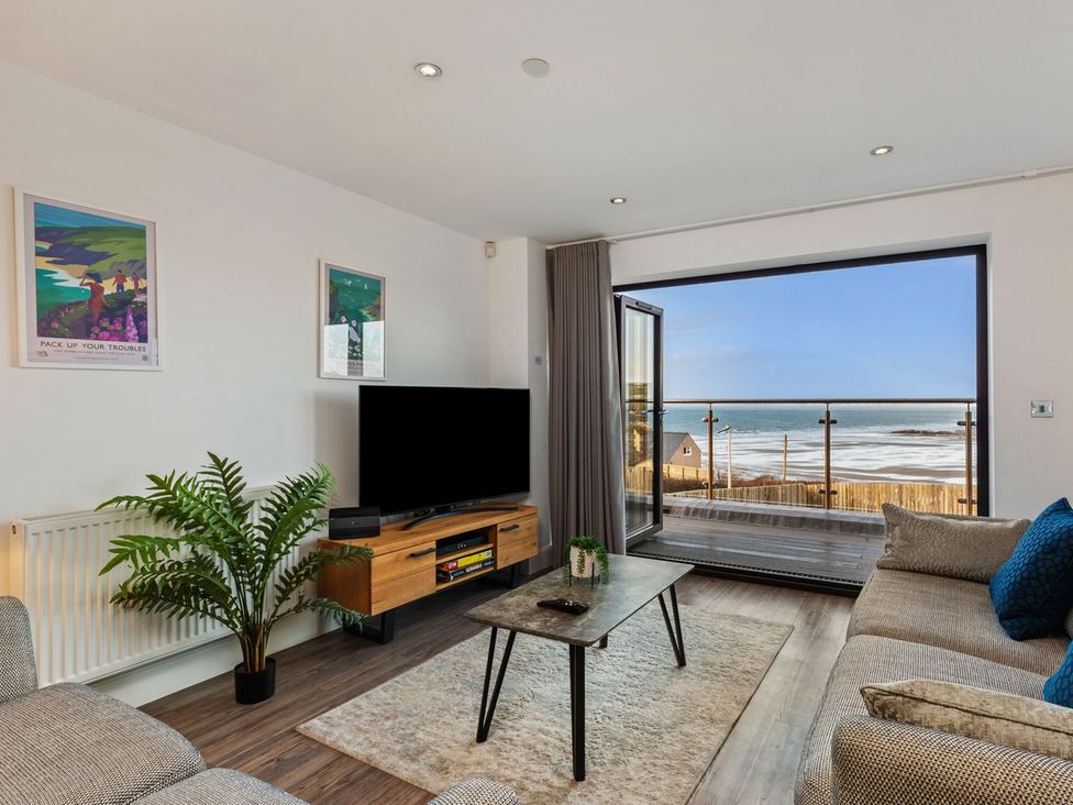 A living room with a sofa and television at One Sand Banks in Haverfordwest