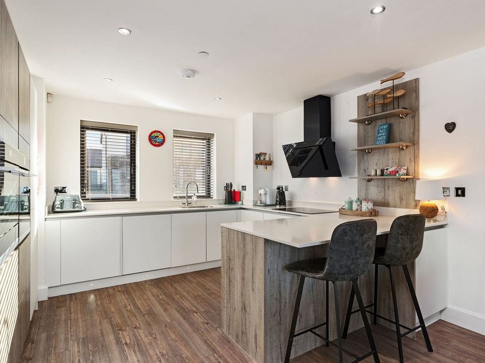 A kitchen with an island and bar stools at One Sand Banks in Haverfordwest