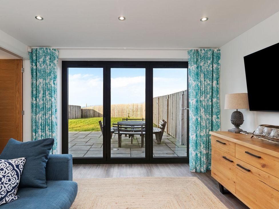 A living room with a sliding door leading to a patio at One Sand Banks in Haverfordwest