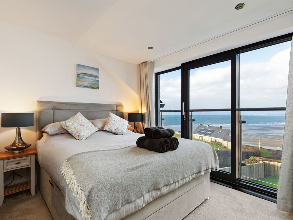 A bedroom with a bed and view of the ocean at One Sand Banks in Haverfordwest